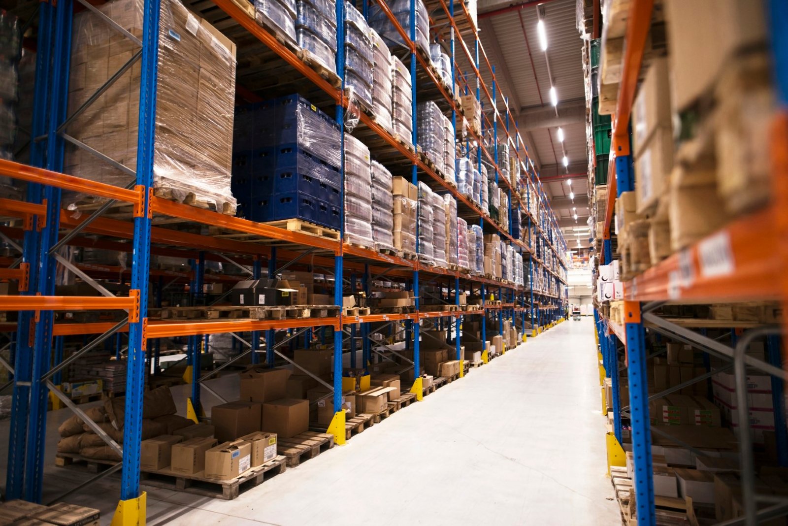 Interior of large distribution warehouse with shelves stacked with palettes and goods ready for the market.